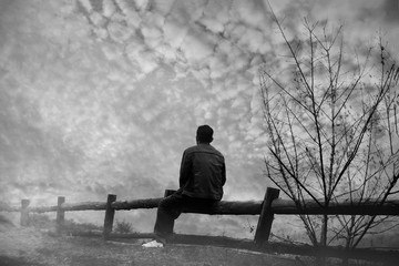 A lone men sitting in the fog on the mountain