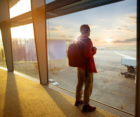 Back view of young  backpacker man which take a picture on the window by smartphone at a terminal airport