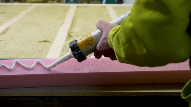 Carpenter putting glue on polystyrene insulation in wood house