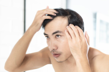 Close up man looking reflection in the mirror serious hair loss problem for health care shampoo and...
