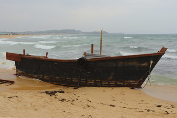 Korean fishing boat wreck on sandy sea beach after the storm. Broken boat of poor north korean fishermen.