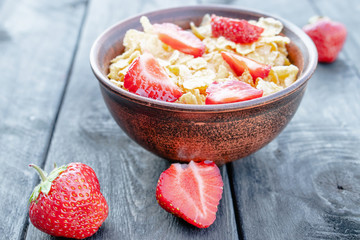 Fresh homemade muesli, muesli with strawberries in a plate on a dark gray background, selective focus