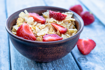 Fresh homemade muesli, muesli with strawberries in a plate on a blue background