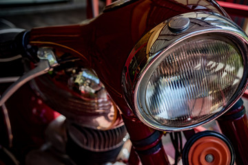 A fragment of a classic motorcycle, headlight and gas tank.