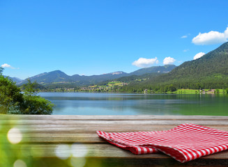 Empty wooden table with checkered napkin outdoors, space for design. Summer picnic