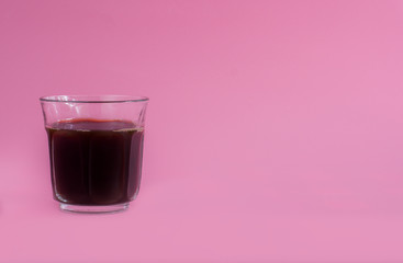 Glass of black coffee on pink background. Beverage morning concept.