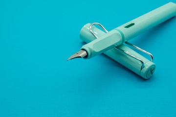 Blue calligraphic pen on blue background with depth of field.