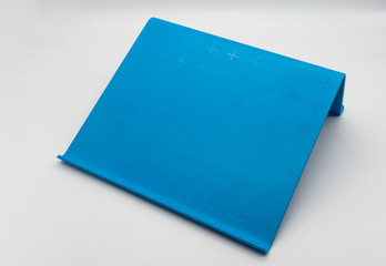 White digital tablet on blue plastic tablet stand isolated on white