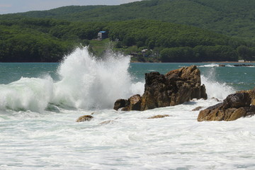 Big storm waves hitting the coastal rocks of the sea. Sunny windy day, blue sky. Splashes and foam....