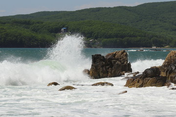 Big storm waves hitting the coastal rocks of the sea. Sunny windy day, blue sky. Splashes and foam....