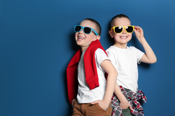 Portrait of cute twin brothers with sunglasses on color background. Space for text - obrazy, fototapety, plakaty