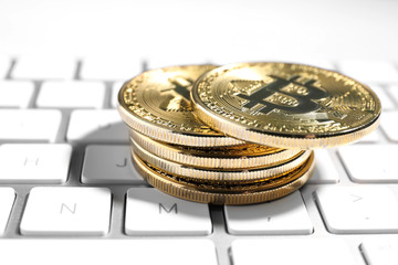 Golden bitcoins on white computer keyboard, closeup view
