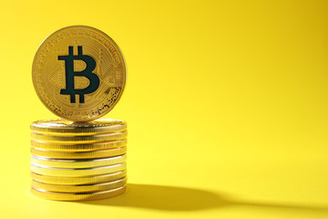 Stack of bitcoins on color background, space for text. Digital currency