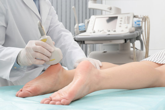 Doctor conducting ultrasound examination of patient's foot in clinic, closeup