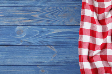 Checkered picnic blanket on color wooden background, top view. Space for text
