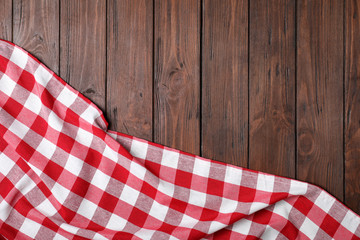Checkered picnic blanket on wooden background, top view. Space for text
