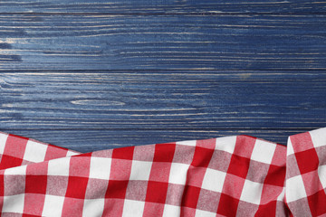 Obraz premium Checkered picnic blanket on color wooden background, top view. Space for text
