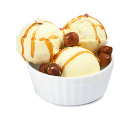 Delicious ice cream with caramel sauce and hazelnuts in dessert bowl on white background