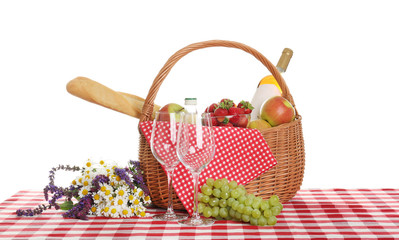 Picnic basket with wine and food on tablecloth against white background