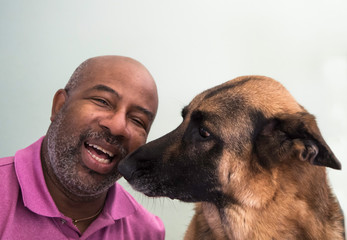 Cute moment between an African American man and his German Shepherd dog who is giving kisses