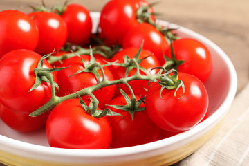 Fresh cherry tomatoes in bowl on table, closeup