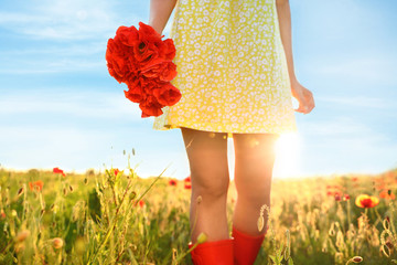 Woman with bouquet of poppies in sunlit field, closeup