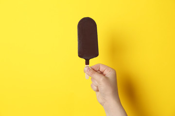 Woman holding delicious ice cream with chocolate against color background