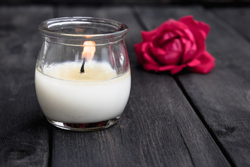 Rose and burning candle on an old wooden board. Flower frame.