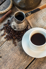 coffee cup, metal turk and coffee beans on a wooden background