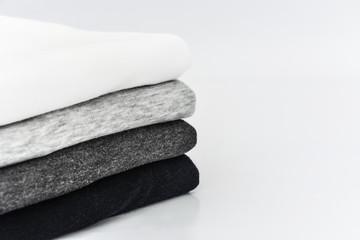stack of folded black, grey and white color tone (monochrome) t-shirt on white background, copy...