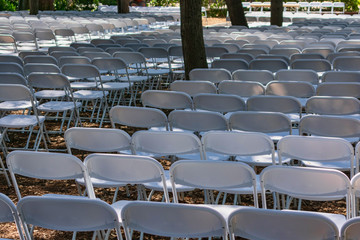 Rows of white folding chairs set up outside for ceremony, event or party