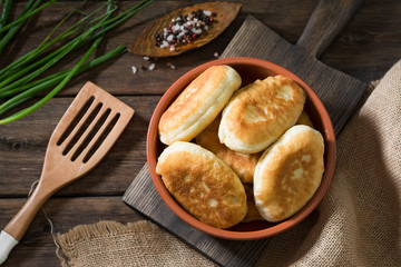 Pies in a ceramic bowl on a wooden background. National dish. Rustic style