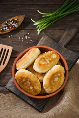 Pies in a ceramic bowl on a wooden background. National dish. Rustic style