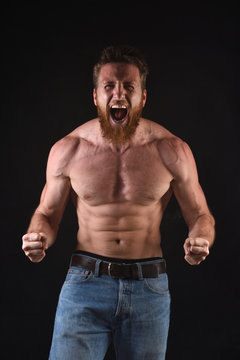 angry shirtless man in black background