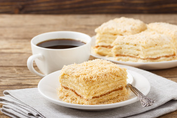 Piece of cake with cup of coffee on wooden table.