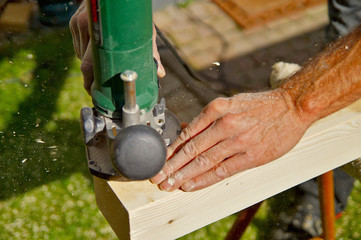 Processing of Natural Wooden beam with milling woodworking machine. Milling machine for wood. male Hand of carpenter holds a carpentry tool. Man processes wood detail with fraser on manufacture. 