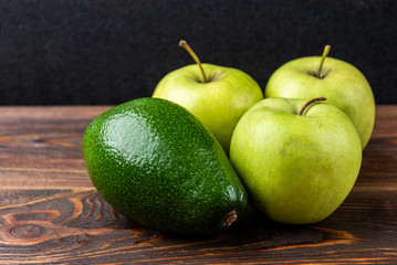 Avocado and green apple on dark wooden background.
