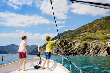Two adorable school kid boys, best friends enjoying sailing boat trip. Family vacations on sea on sunny day. Children smiling. Brothers, schoolchilden, siblings, best friends having fun on yacht.