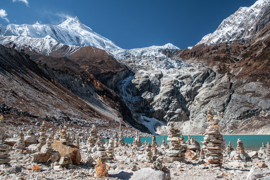 Stonemen and a  beautiful view of Manaslu mountain range, Birendra lake.  Lake and stone walls in front of snowy Mount Manaslu (8 156 meters) Birendra Lake, Himalayas, Nepal