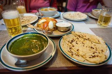 Typical nepalese meal and beer in Pokhara restaurant, Himalayas, Nepal. Assorted indian nepalese food on table. Dishes and appetizers of indian cuisine. Curry, butter chicken, rice, lentils, paneer, s