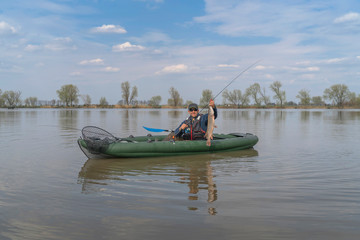 Fototapeta na wymiar Kayak fishing. Fisherman caught pike fish on inflatable boat with fishing tackle at lake.