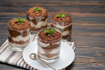 Classic tiramisu dessert in a glass on wooden background