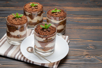 Classic tiramisu dessert in a glass on wooden background