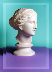 White gypsum copy of ancient statue Venus head on a green purple background. Plaster sculpture...