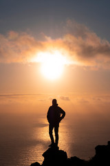 Fototapeta premium Man on top of the mountain watching the sunset over the sea, Basque Country, Spain