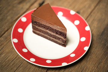 Dark chocolate cake with red white plate on wood table