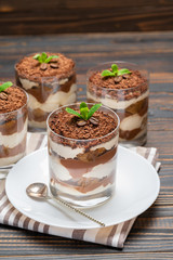 Classic tiramisu dessert in a glass on wooden background