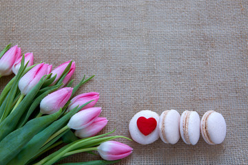 Mother's day background with tulips bouquet and pink macarons.