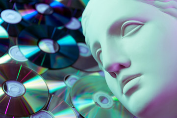 Antique statue of Venus head close up on a glitter CDs background. Concept of music, style, vintage.