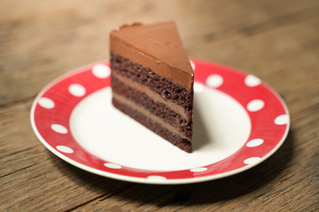 Dark chocolate cake with red white plate on wood table